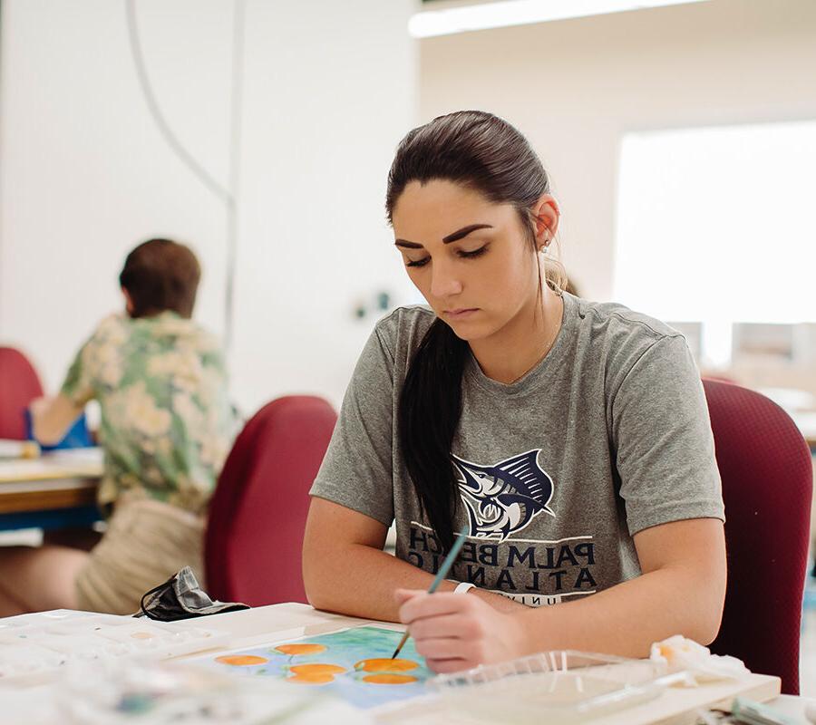 an art education student painting at a table